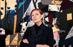 Professor Sally Smart standing in front of a textile artwork.