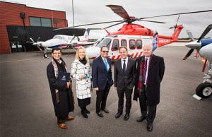 A group of people standing in front of a medical helicopter.
