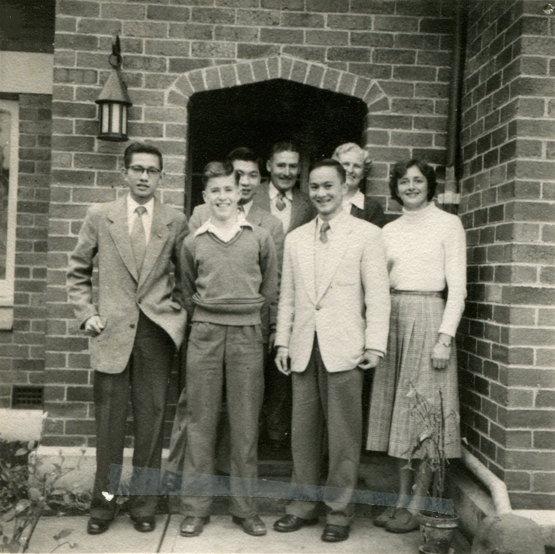 A group of people including Olive Wykes standing outside a brick building.
