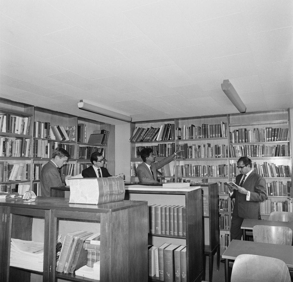 Black and white photograph of four male students in the library at International House, The University of Melbourne