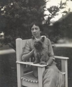 Black and white photograph of Lady Mabel Grimwade seated in a garden with a small dog on her lap.