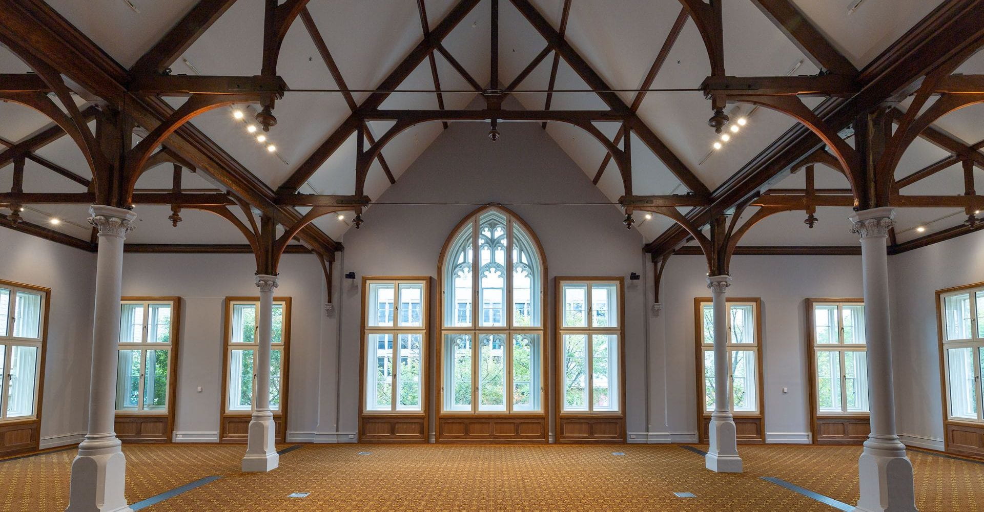 Photography of large interior room with orange carpet and high arched windows