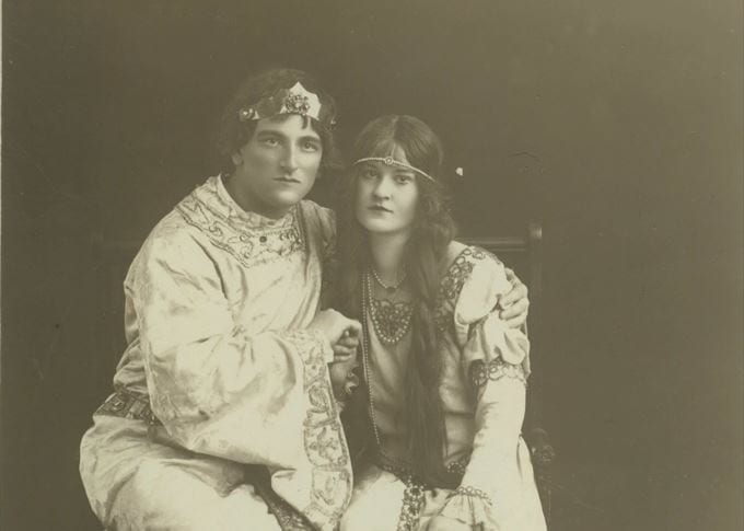 Photo of seated man and woman in sepia tones, wearing theatrical costumes