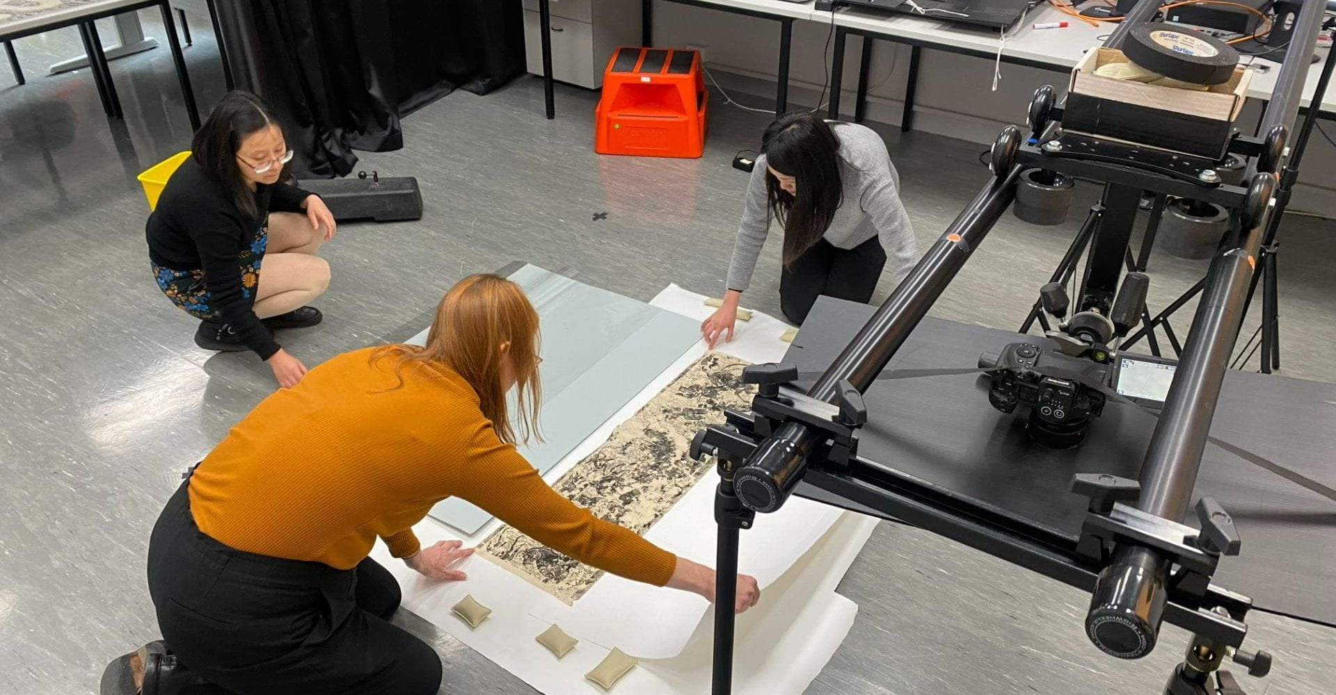 Three staff arranging stone rubbings from the Harry Simon Collection for photogrammetry capture at the UDC