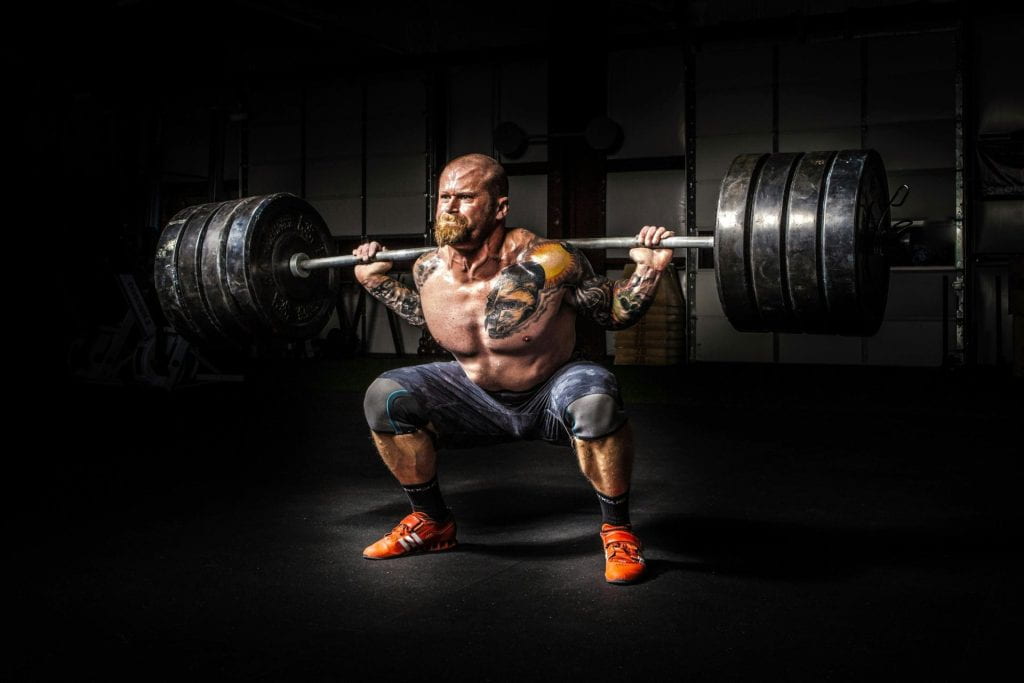 A weightlifter exerting a lot of energy to lift a heavy weight.